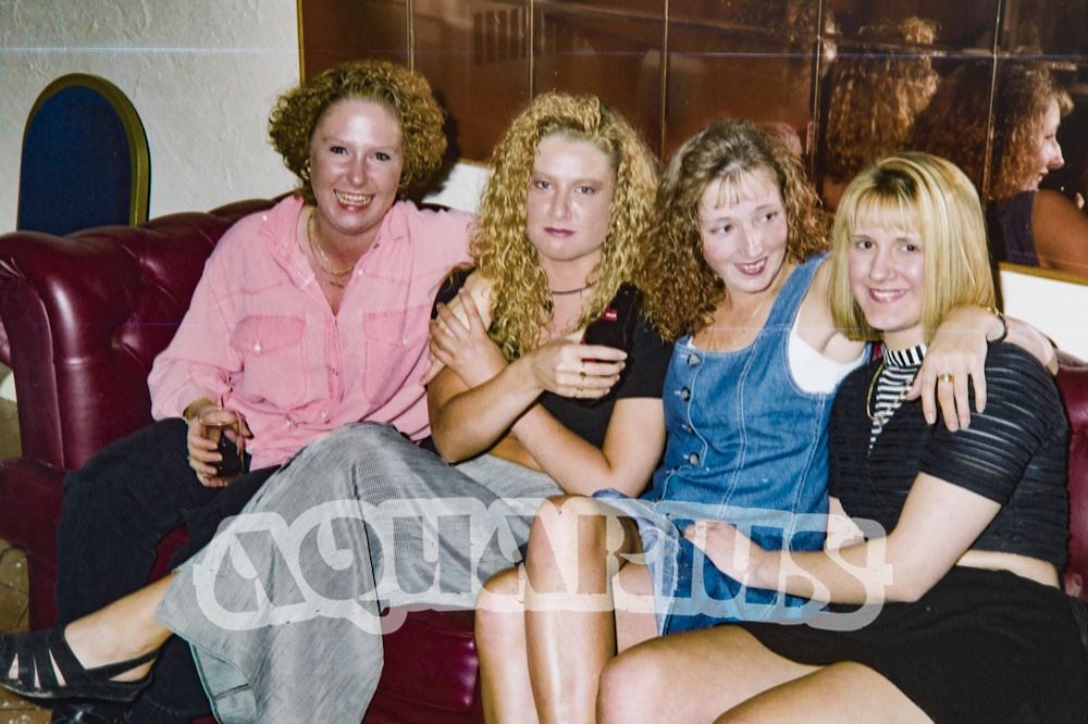 Customers on a red leather sofa in front of bronze mirror tiles