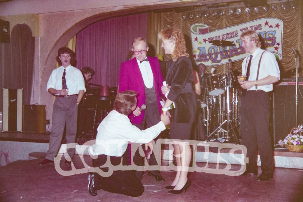 Compere Tufty Gordon on stage with customers, in front of the house band