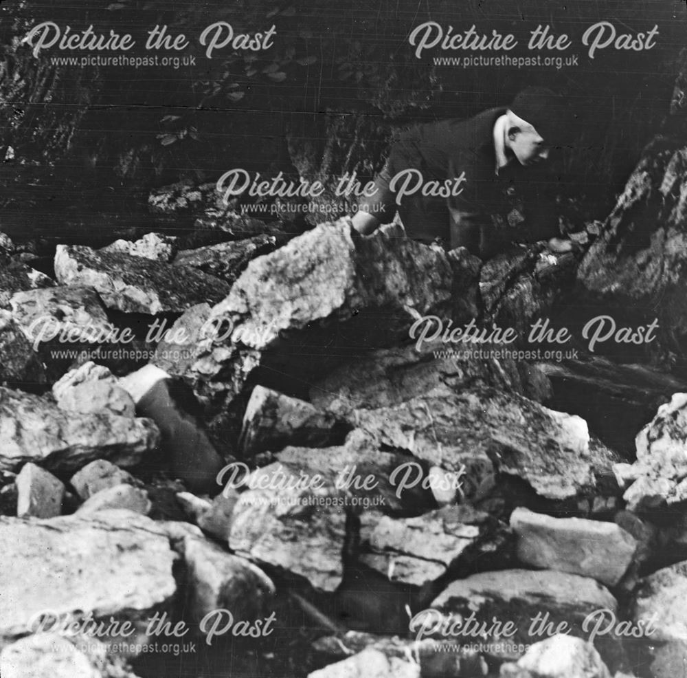 Boy scrambling over rocks, unknown location, c 1930s