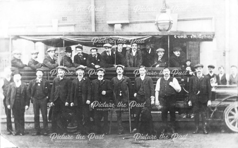 Group of men posed by an excursion bus