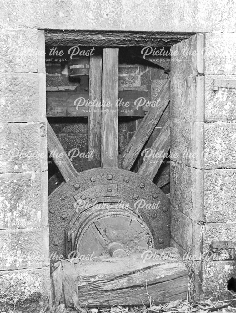 Interior of former mill before restoration, showing water wheel in situ.