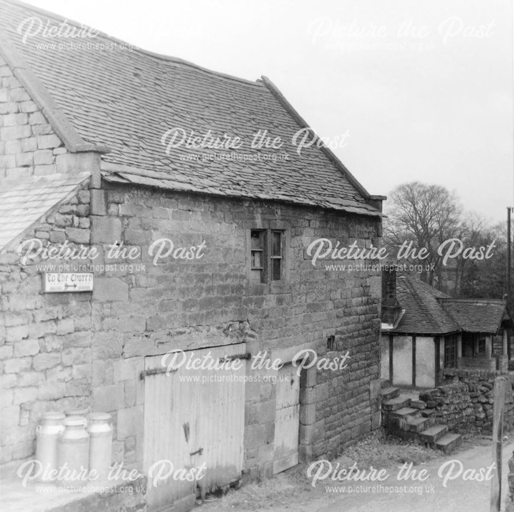 Milk churns outside a stone barn