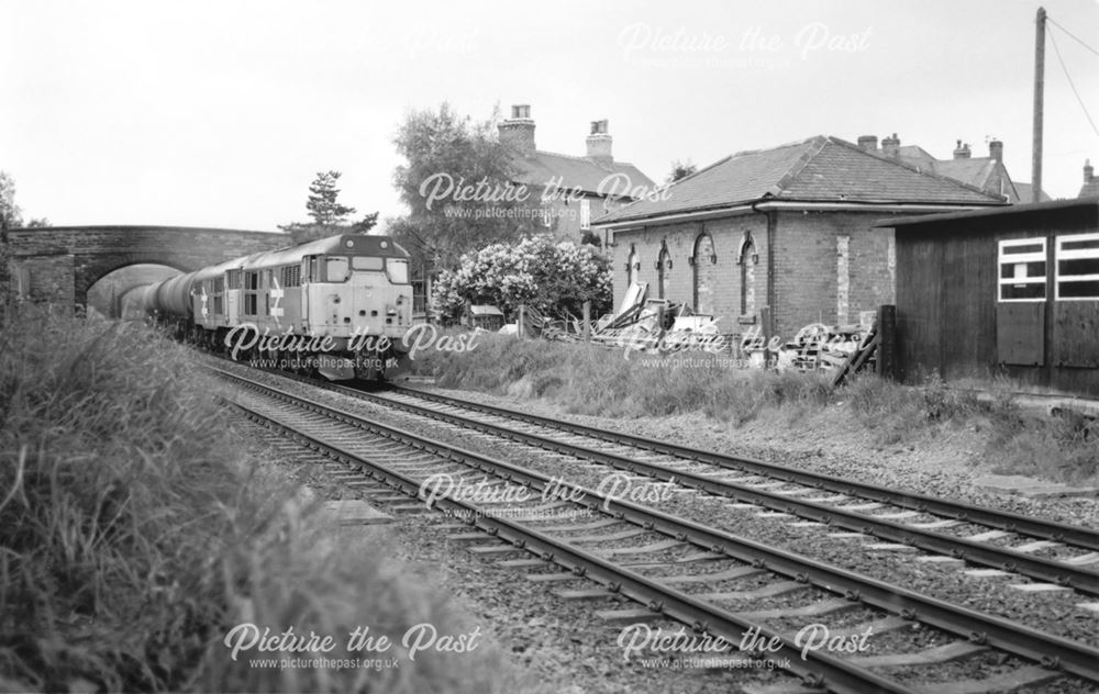 A train passes derelict railway station buildings, Weston on Trent
