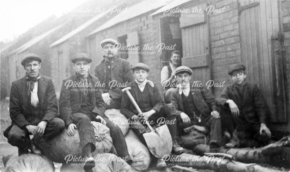 The Grainger Family men and boys sitting on sacks in a yard