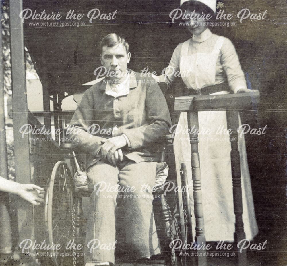 Wounded soldier in wheelchair, with nurse in attendance