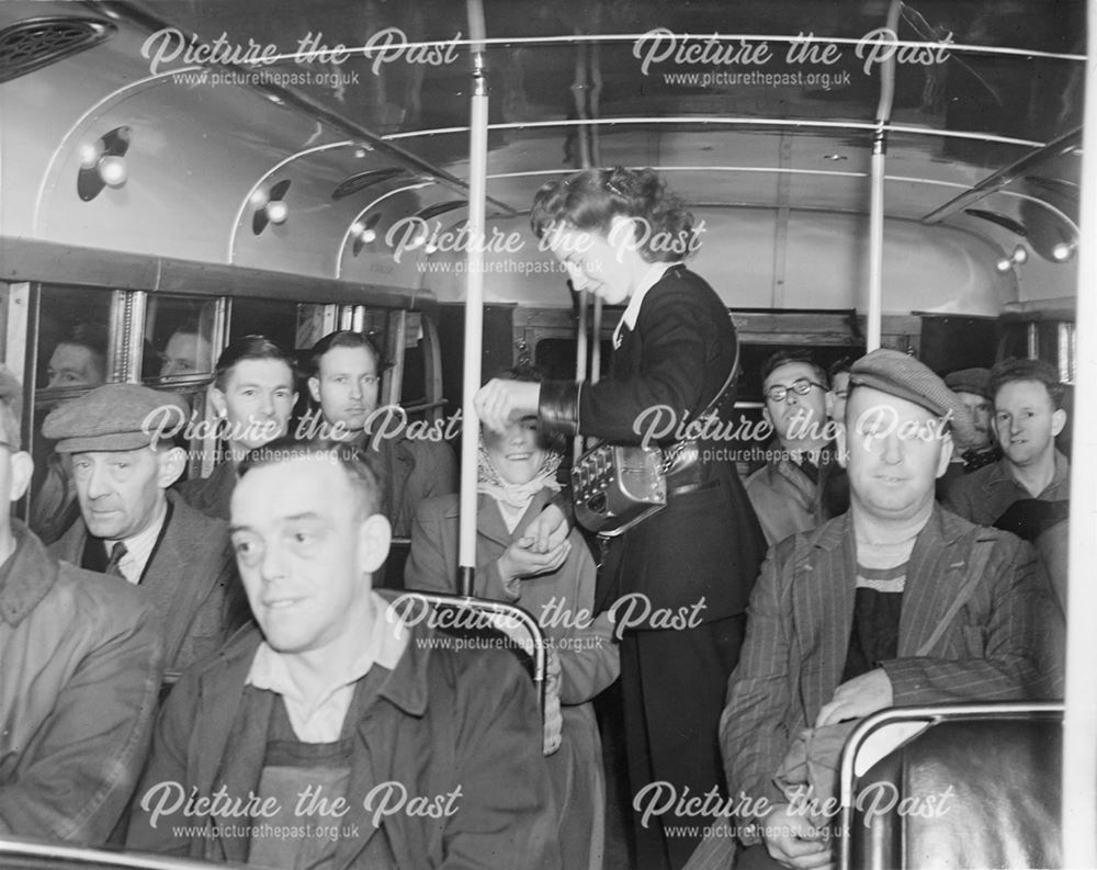 A conductress collecting fares on the upper deck of a Derby Corporation bus.