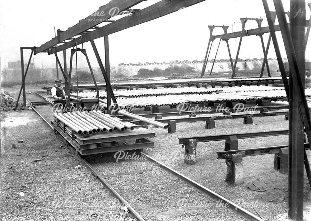 Electric transfer car carrying spun iron pipes being unloaded