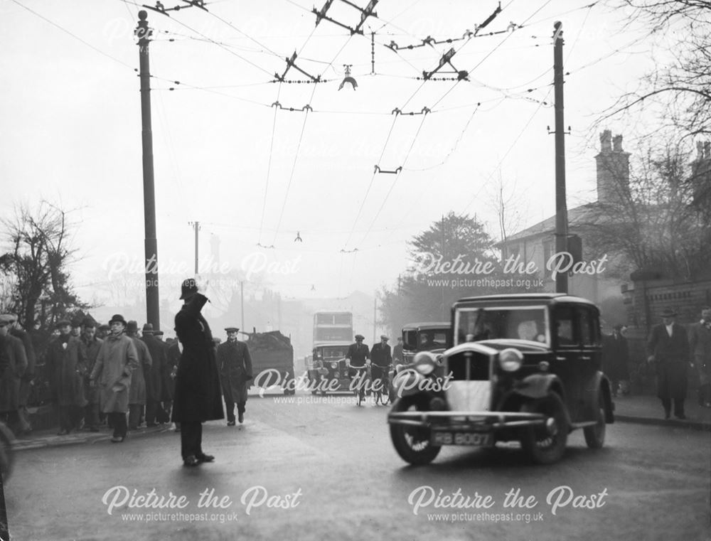 Traffic congestion, trolley bus cables and workers crowd the street on Osmaston Road