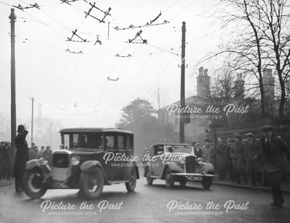 Cars, trolley bus cables and workers crowd the street on Osmaston Road