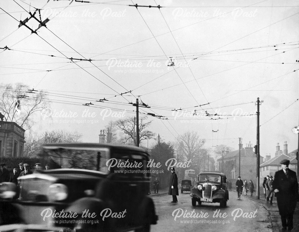 Cars, trolley bus cables and workers crowd the street on Osmaston Road