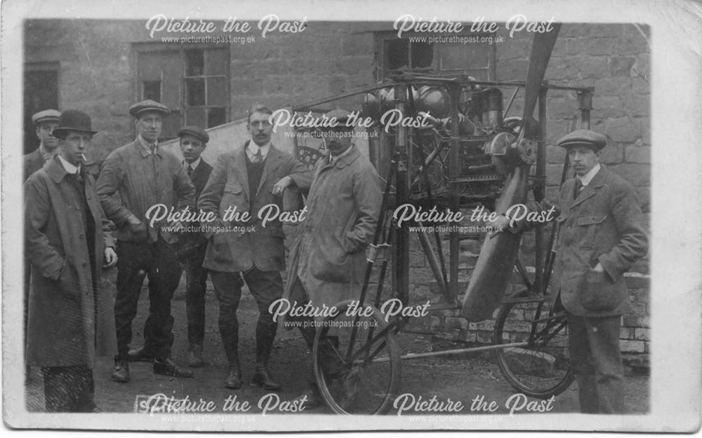Group of unidentified men with aeroplane engine and propellor