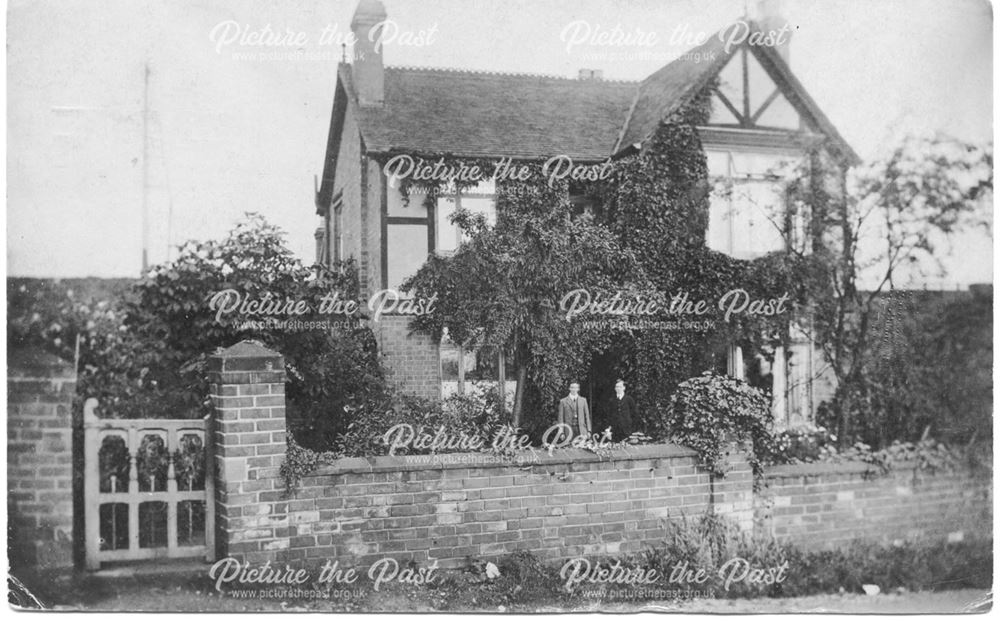 Large house with two men standing in garden.