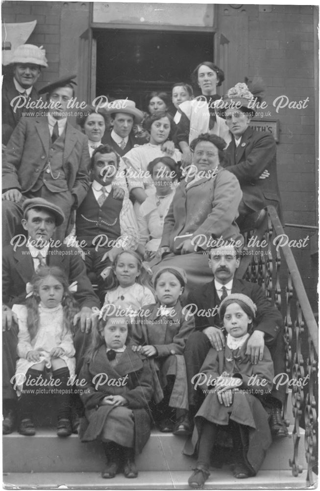 Group of people, including men women and children, posing on a staircase