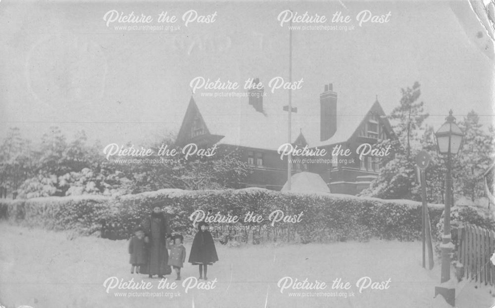 Snowy scene with large house in background, family group in foreground