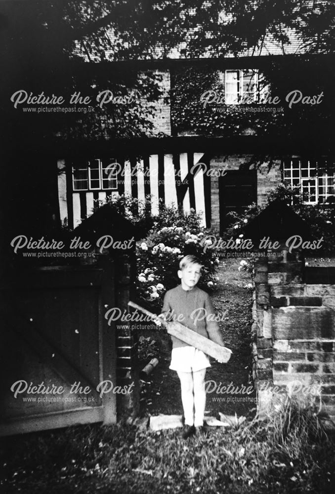 Boy with cricket bat standing outside The Friar's House, The Village, Dale, pre-1977