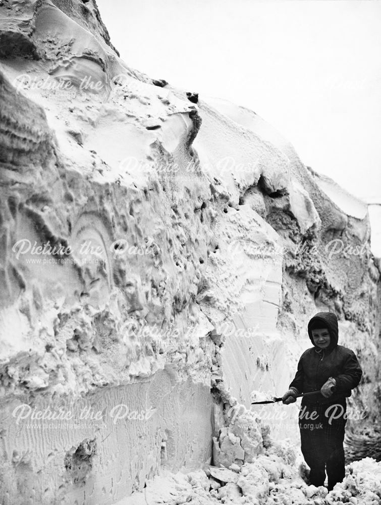 A Young child playing at the side of a huge snow drift, Winter 1963