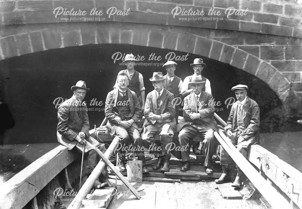 Eight men in a boat at the mouth of Exeter Bridge