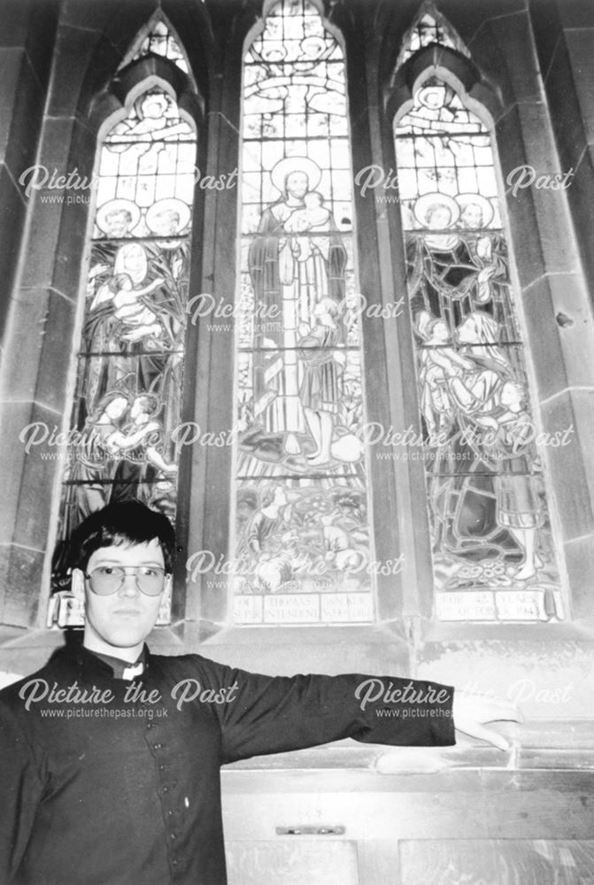 View of St James Church interior, showing a stained glass window and a cleric