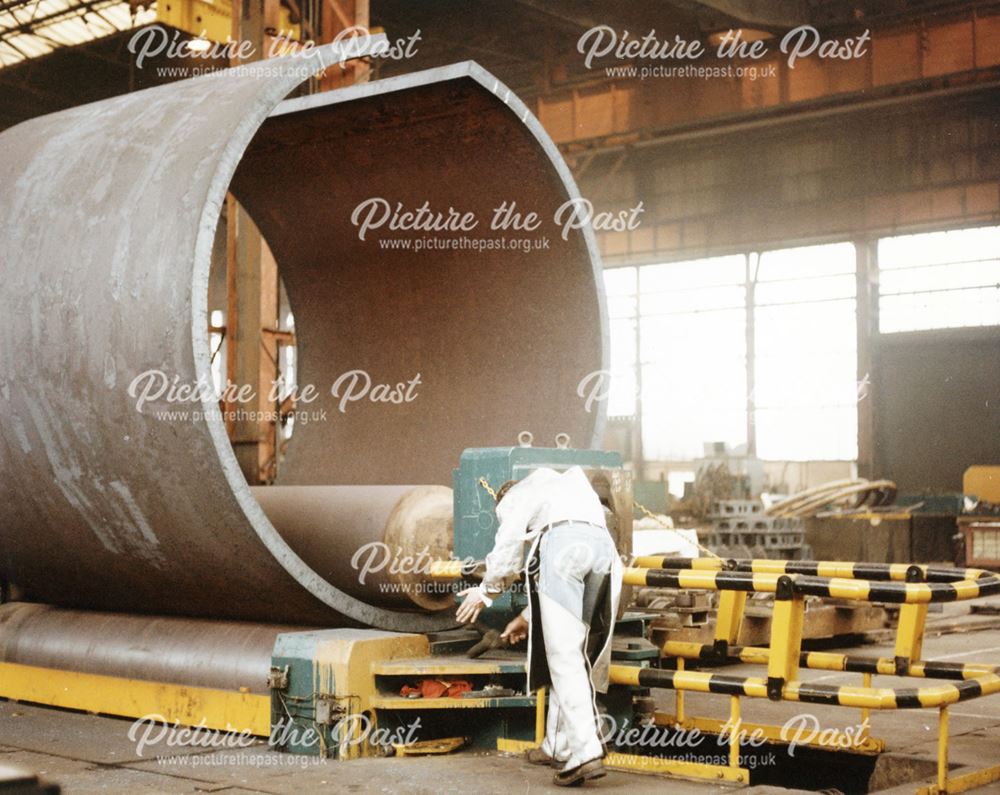 Internationl Combustion Limited - Employee operating a rolling machine to form a large metal tube